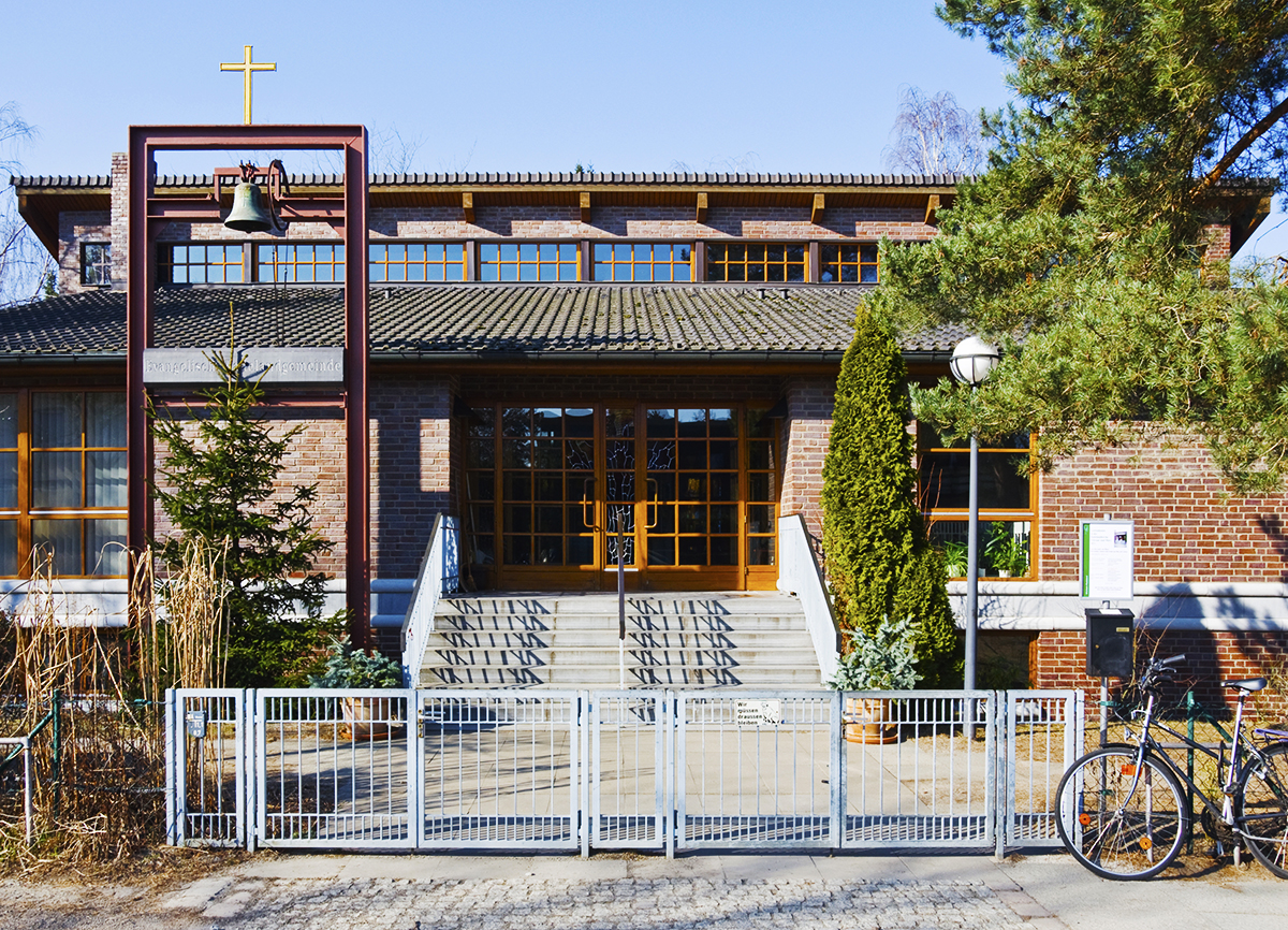 Gemeindezentrum Radeland: Ein japanisch anmutendes Gebäude mit Holzrahmentüren und Fenstern, ein freistehendes Gestell mit Glocke steht im Vorgarten.