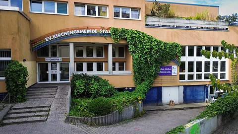 Ernst-Lange-Haus, ein postmoderner Bau, über dem Eingang steht halb überrankt "Ev. Kirchengemeinde Staaken"