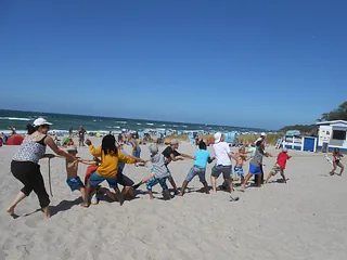 Kinder spielen Tauziehen am Strand