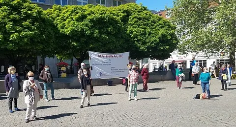 Mitglieder der Mahnwache stehen mit ihrem Banner auf dem Spandauer Altmarkt