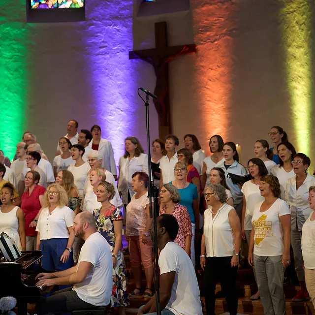 Chor singt vor einer bunt angestrahlten Wand