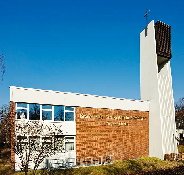 St. Petruskirche: ein moderner Kirchenbau, Front mit Klinker verkleidet, weißer Turm mit Kreuz