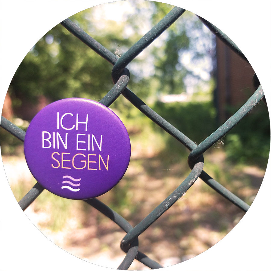 Symbolbild: An einem Zaun hängt ein Button "Ich bin ein Segen"