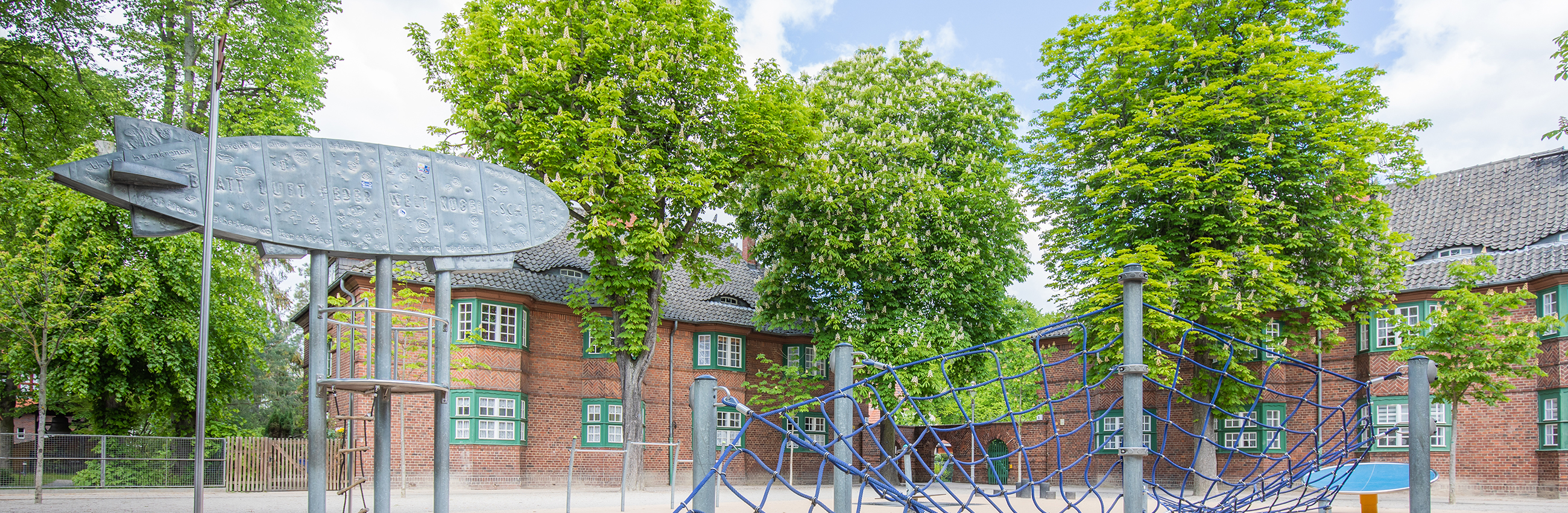 Schulhof der Zeppelingrundschule, gegenüber der Kirche, zweigeschossige Backsteingebäude, Kastanienbäume und ein Spielplatz