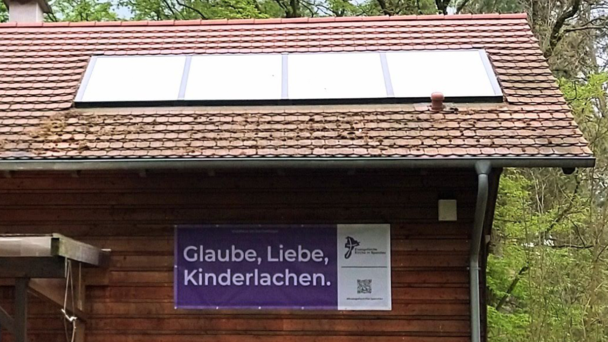 Lila Banner am Haus: Glaube, Liebe, Kinderlachen.