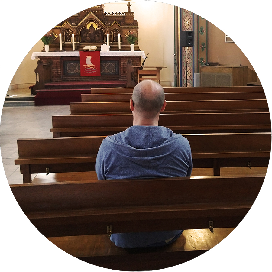 Symbolbild: Ein Mensch sitzt in einer Kirchenbank